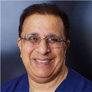 A man with glasses wearing a blue shirt smiles at the camera against a blurred dark background.