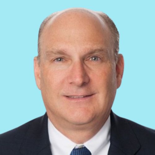 Portrait of a man with a receding hairline, wearing a dark suit jacket, white shirt, and a dark blue tie, set against a light blue background.